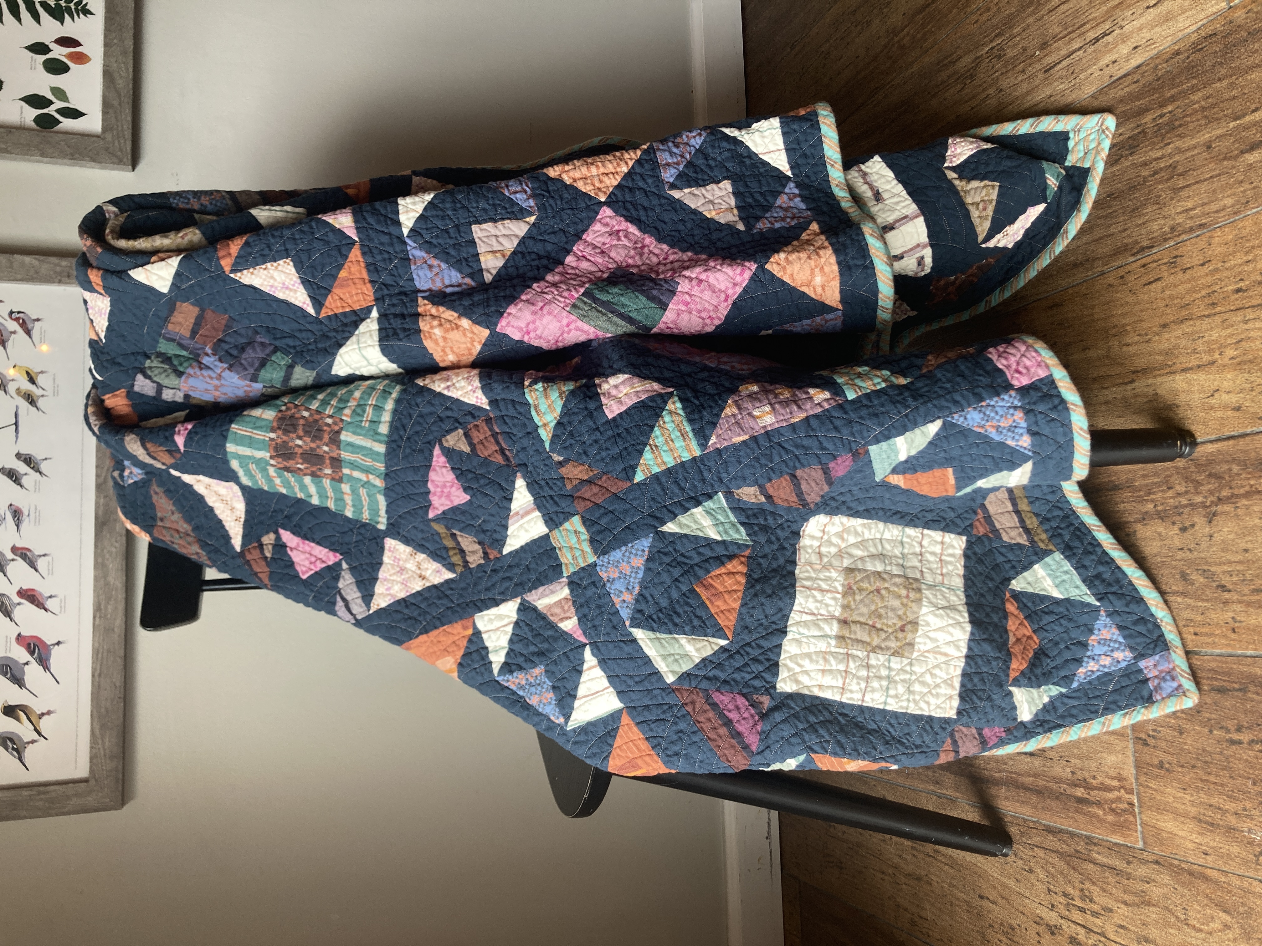 A navy quilt with scattered triangle blocks in woven fabrics, draped over a chair